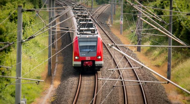 Powiększ obraz: czerwony pociąg jadący po torach